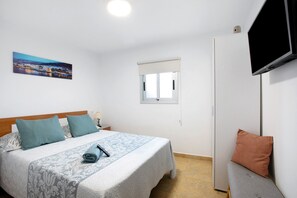 Un dormitorio con una cama, un televisor, una ventana y un cuadro.