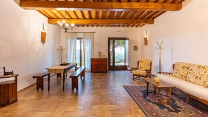 A spacious living room with a wooden ceiling, a sofa, a bench, a table, and a patterned rug. - Apartment "Agriturismo Il Casato Mag-il Giogo" with Mountain View, Terrace and Wi-Fi (Pienza)