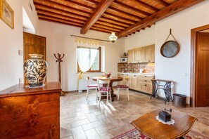 A rustic kitchen with wooden cabinets, a dining table with chairs, a wooden floor, and a hanging light fixture. - Apartment "Agriturismo Il Casato Mag-il Vaglio" with Mountain View, Terrace and Wi-Fi (Pienza)