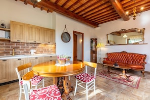 A kitchen with wooden cabinets, a dining table with chairs, a red sofa, and a mirror on the wall. - Apartment "Agriturismo Il Casato Mag-il Vaglio" with Mountain View, Terrace and Wi-Fi (Pienza)
