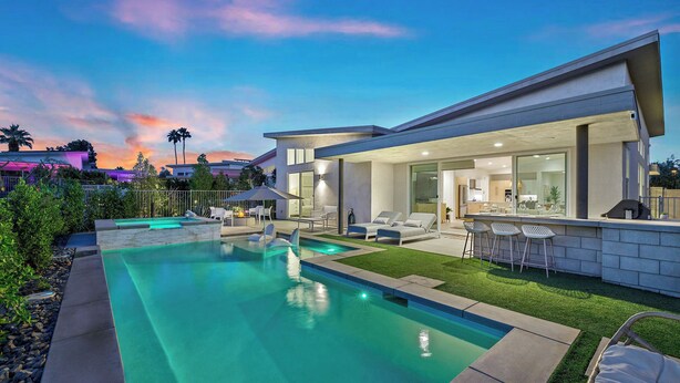 Une maison moderne dotée d’une piscine, d’un espace salon extérieur et d’une pelouse bien entretenue.