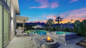 Une terrasse extérieure moderne avec une piscine, des chaises longues et un foyer.