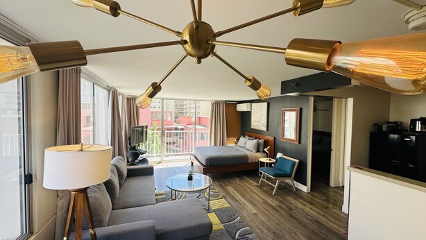 A modern hotel room with a large bed, a sofa, a dining table, and a kitchen area. - Contemporary Waikiki Beach Condo with Rooftop Pool, Superb Shopping and Dinning  (Honolulu)
