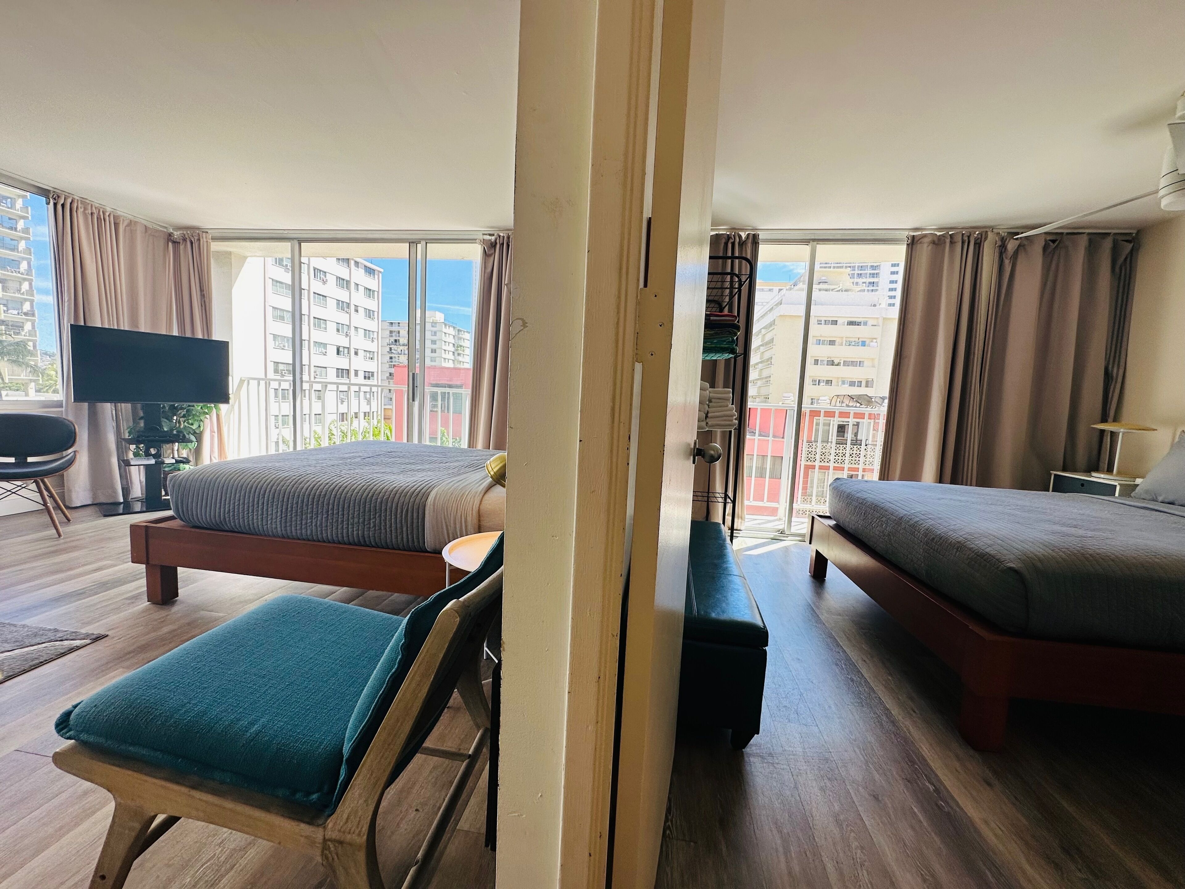 Een hotelkamer met een bed, een stoel, een televisie en uitzicht op de stad.