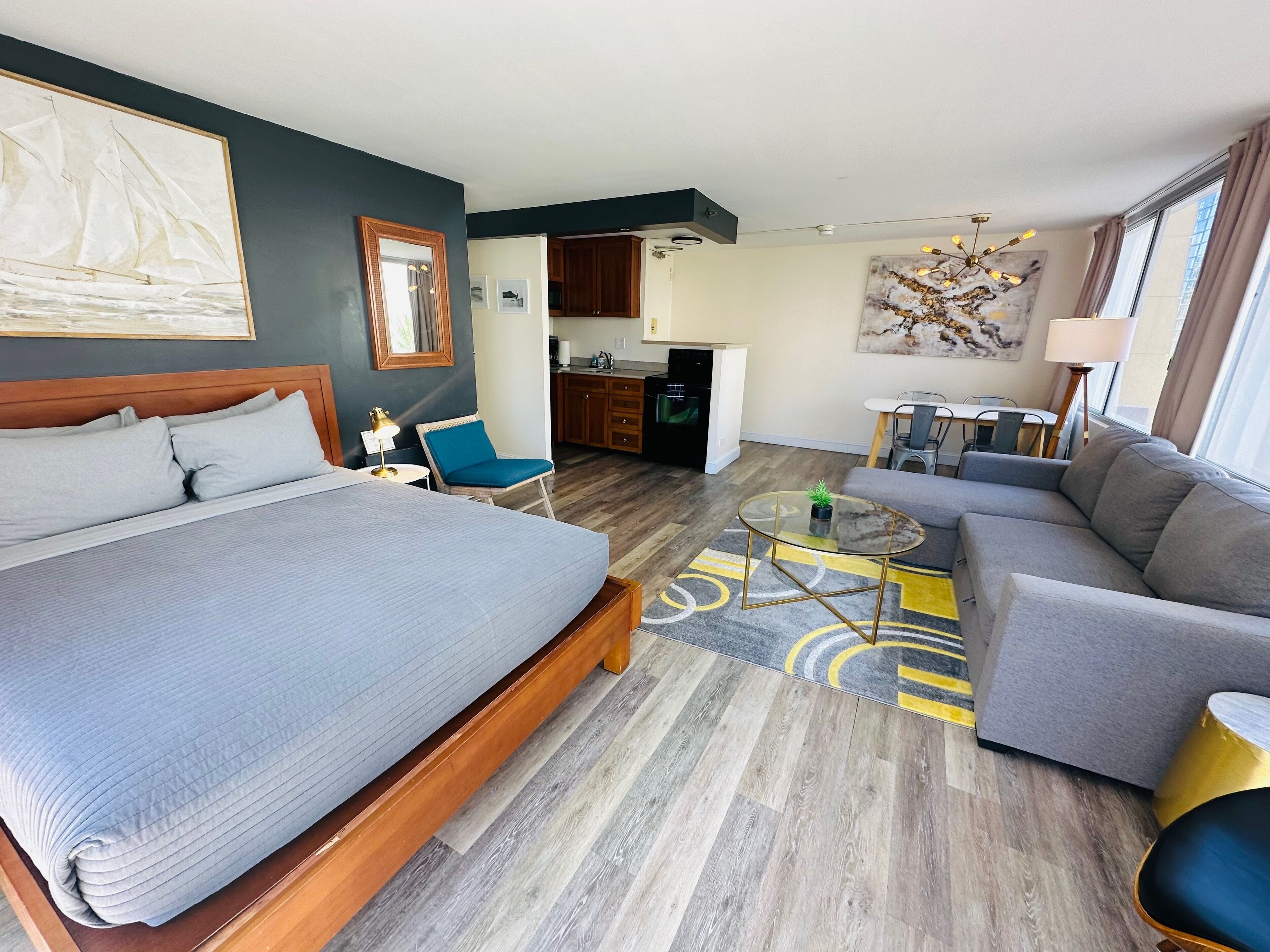 Ein Hotelzimmer mit einem großen Bett, einer Couch, einem kleinen Tisch und einer Küchenzeile.