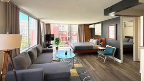 A modern hotel room with a sofa, a bed, a small table, and a balcony with a view of the city. - Contemporary Waikiki Beach Condo with Rooftop Pool, Superb Shopping and Dinning  (Honolulu)