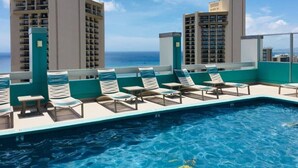 A rooftop pool with lounge chairs and a view of the ocean. - Contemporary Waikiki Beach Condo with Rooftop Pool, Superb Shopping and Dinning  (Honolulu)
