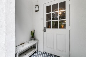 A white door with a window, a small bench, and a wall-mounted light fixture.