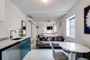 A compact living space with a kitchenette, a dining area, and a sofa with multiple pillows.