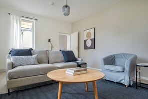 Un salon moderne avec un canapé gris, une table basse ronde en bois et un fauteuil bleu clair.