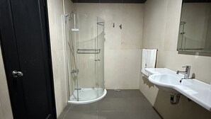 A modern bathroom with a glass-enclosed shower, a white sink, and a large mirror. - Sunset Village (Luperon)