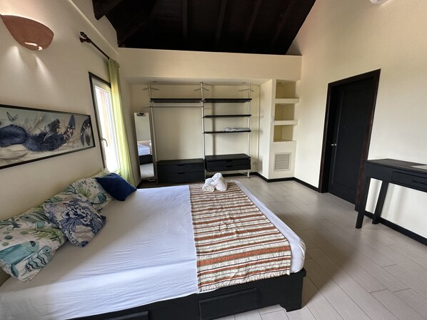 A bedroom with a bed, a dresser, a desk, a wardrobe, and a mirror.