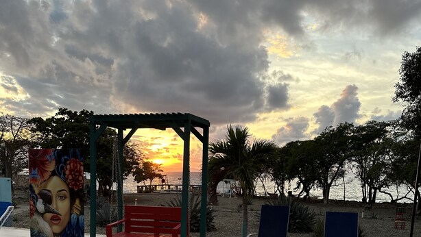 A swimming pool with lounge chairs and a pergola with artwork. - Sunset Village (Luperon)