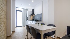A modern kitchen with a white countertop, black range hood, and a dining area with a white table and four chairs. - VLC HOST - Fray Pedro A (Valencia)