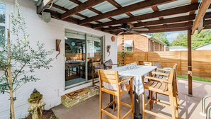 An outdoor patio with wooden furniture, a ceiling fan, and a brick wall in the background.