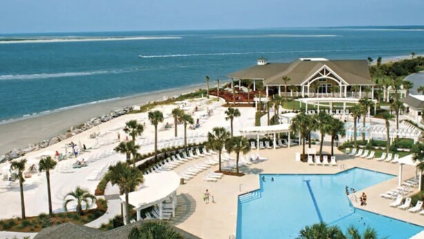 Ein Resort mit großem Pool, Strandbereich und Meerblick.