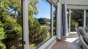 Ein Zimmer mit großen Fenstern und Blick auf einen Garten und Bäume.