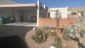 A building with a garage, a patio area with cacti and a sculpture, and a clear blue sky.