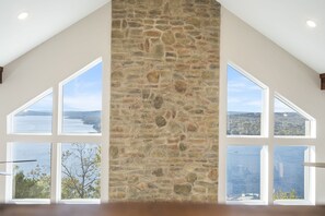Une pièce avec un mur en pierre, de grandes fenêtres et une vue sur un lac.
