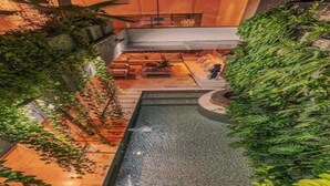 Un área de piscina en la azotea con una fuente central, rodeada de exuberante vegetación y zonas de estar.