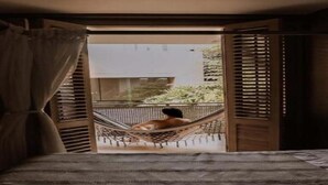 Una habitación con cama, hamaca y vistas al exterior.