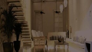 Un amplio salón con una escalera, un sofá, una mesa de centro y una planta en maceta.