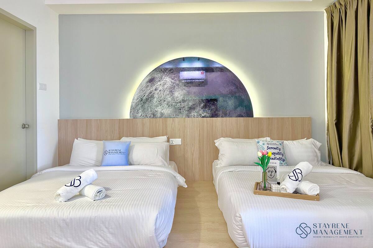 Een hotelkamer met twee bedden, een grote ronde wanddecoratie en een logo op de bedden.