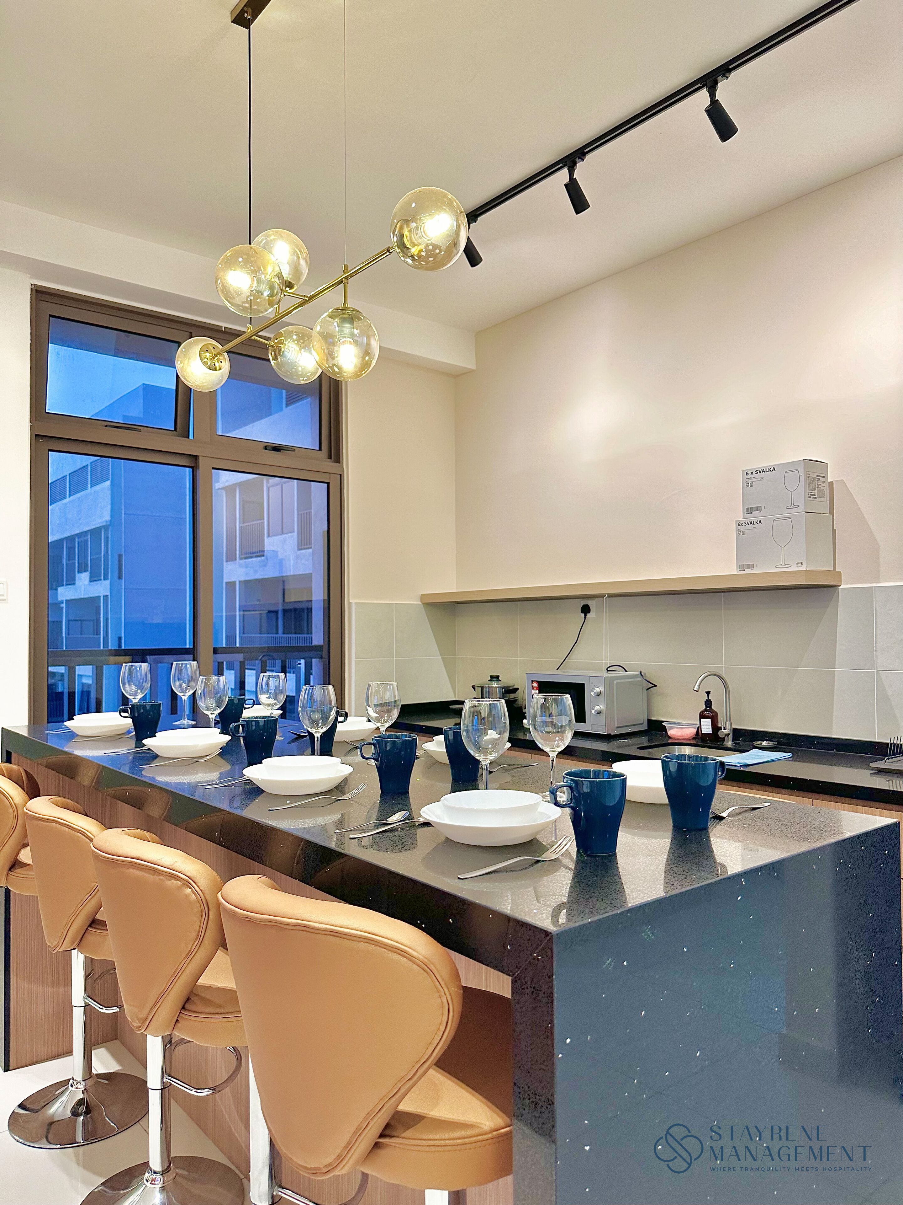 A modern kitchen with a large island, bar stools, and a dining area set up for a meal.