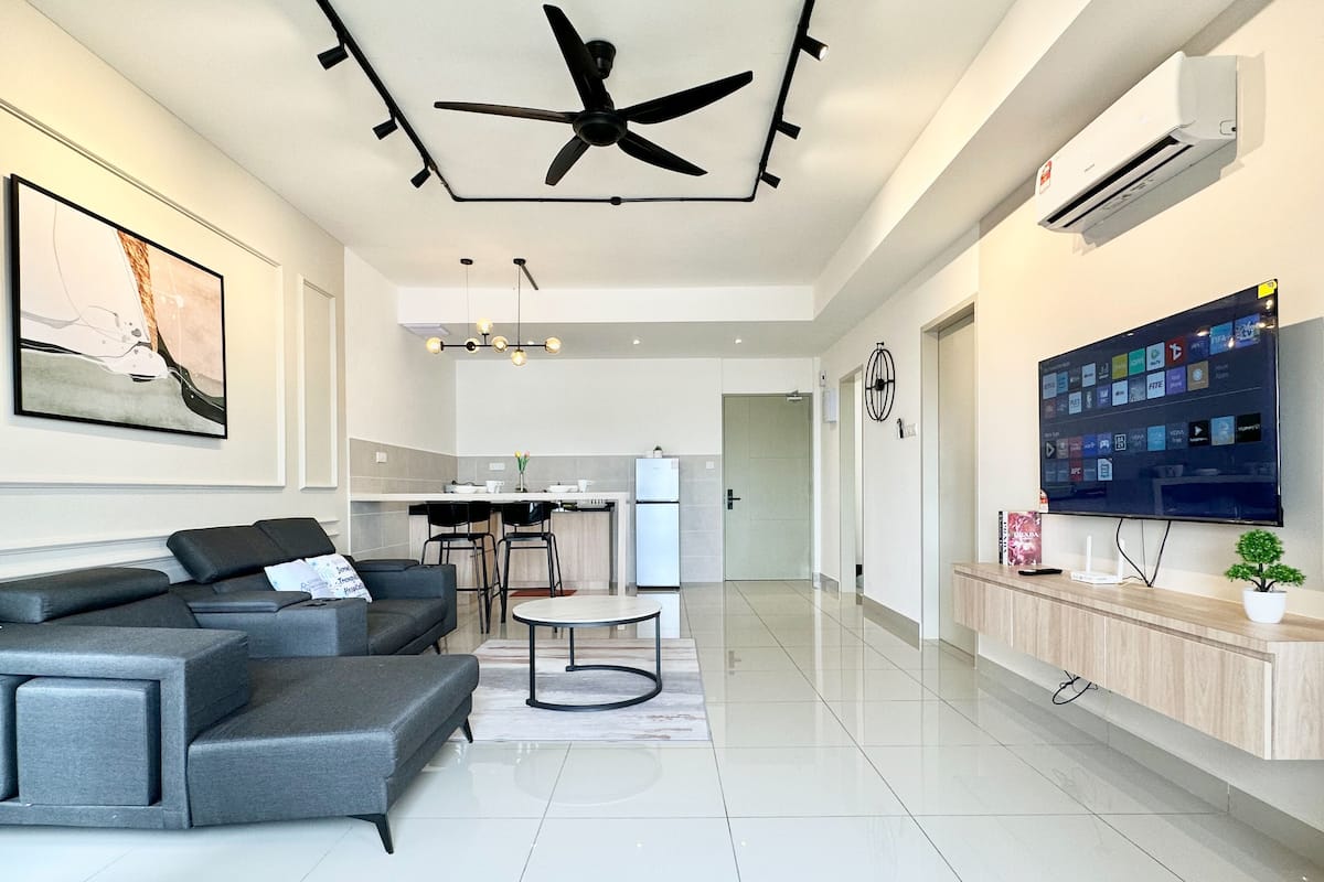Een moderne woonkamer met een grijze bank, een klein rond tafeltje en een plafondventilator.