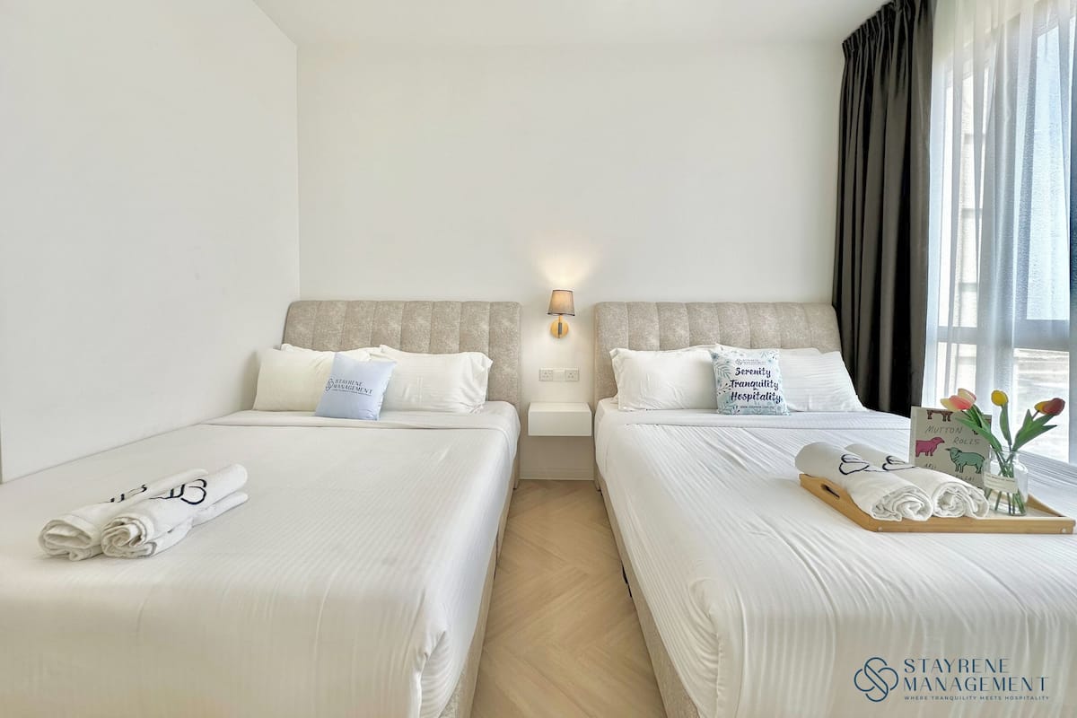 Een hotelkamer met twee bedden, een nachtkastje, een wandlamp en een raam met gordijnen.