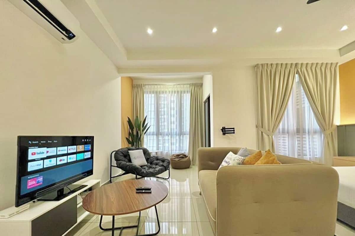 Een moderne hotelkamer met een flatscreen televisie, een bank, een salontafel en een bed.