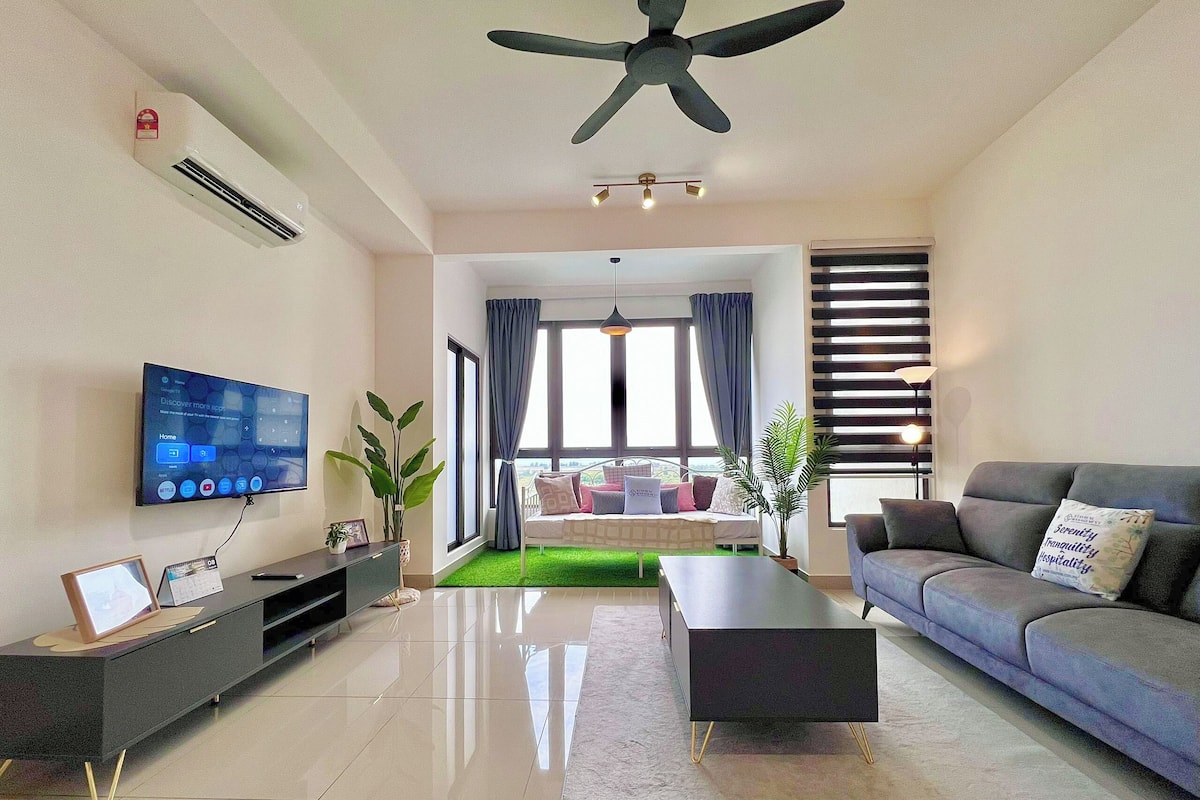 Een moderne woonkamer met een flatscreen televisie, een plafondventilator, een bank, een salontafel en een groen vloerkleed.