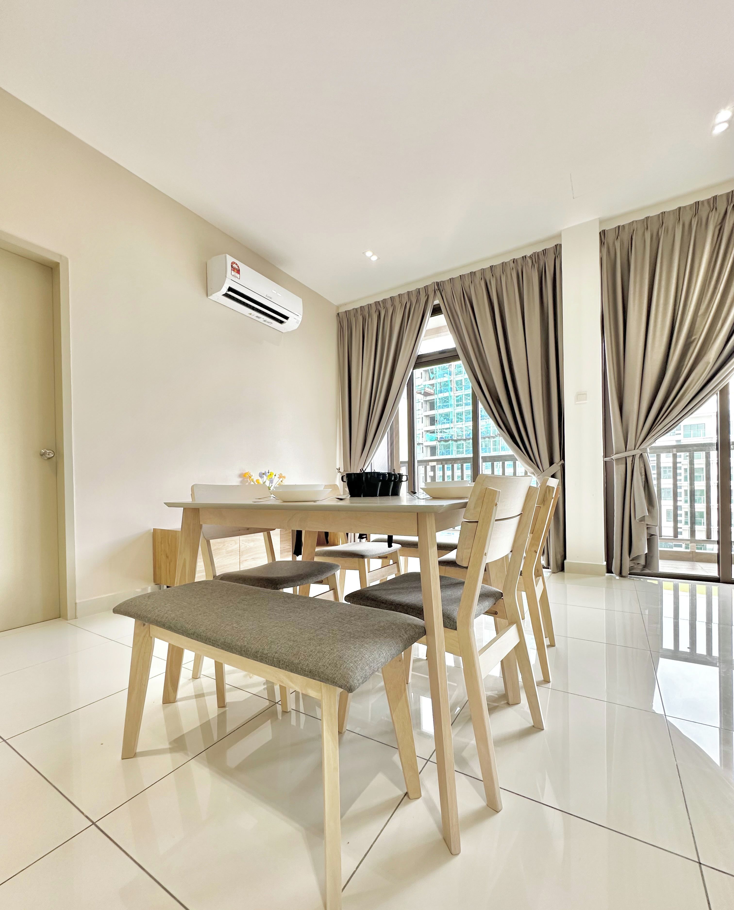A modern dining area with a wooden table and chairs, an air conditioning unit, and large windows with curtains.