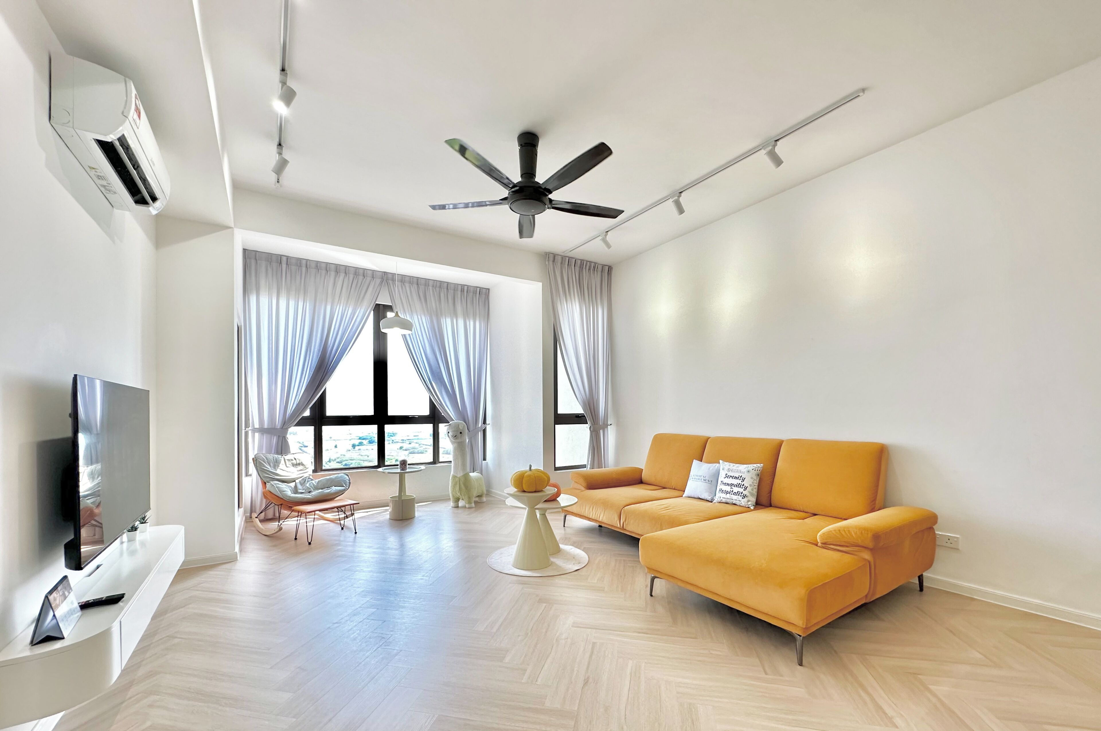 A modern living room with a sofa, TV, and a ceiling fan.