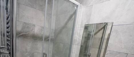 A modern bathroom with a glass-enclosed shower, a white sink, and a toilet.