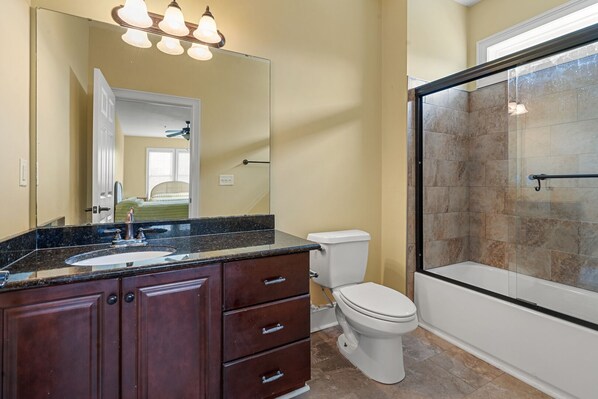 A bathroom with a large mirror, a sink, a toilet, and a glass shower enclosure.