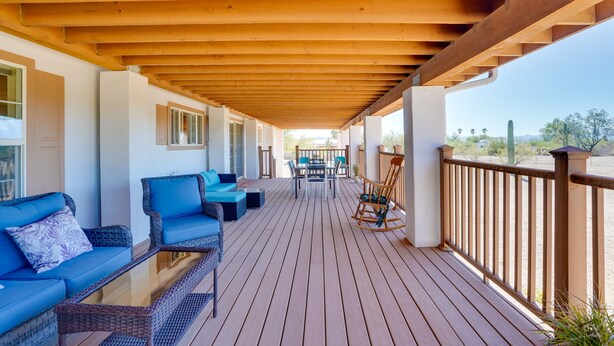 A wooden deck with outdoor furniture, including sofas and a rocking chair, and a view of the desert landscape. - 11 Mi to Saguaro Nat'l Park! Family Home w/ Deck (Tucson)