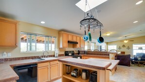 A spacious kitchen with wooden cabinets, a dishwasher, a stove, and a microwave. There is a dining area with a table and chairs. - 11 Mi to Saguaro Nat'l Park! Family Home w/ Deck (Tucson)