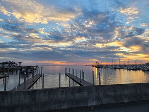 A marina with docks and boats, a bridge in the background, and a sunset sky.