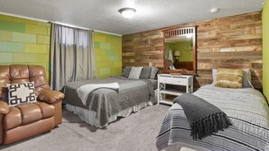 Une chambre avec deux lits, une tête de lit en bois, un petit bureau et un fauteuil en cuir.