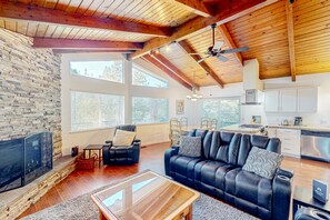 A spacious living room with a fireplace, a black leather sofa, and a wooden coffee table.