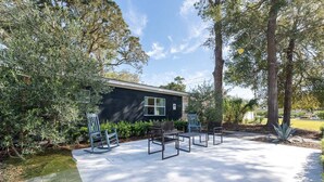 A building with a dark exterior, surrounded by trees and a paved area with benches. - Pet-Friendly St. Simons Island Beach Rental | The Blue Pearl (Saint Simons Island)