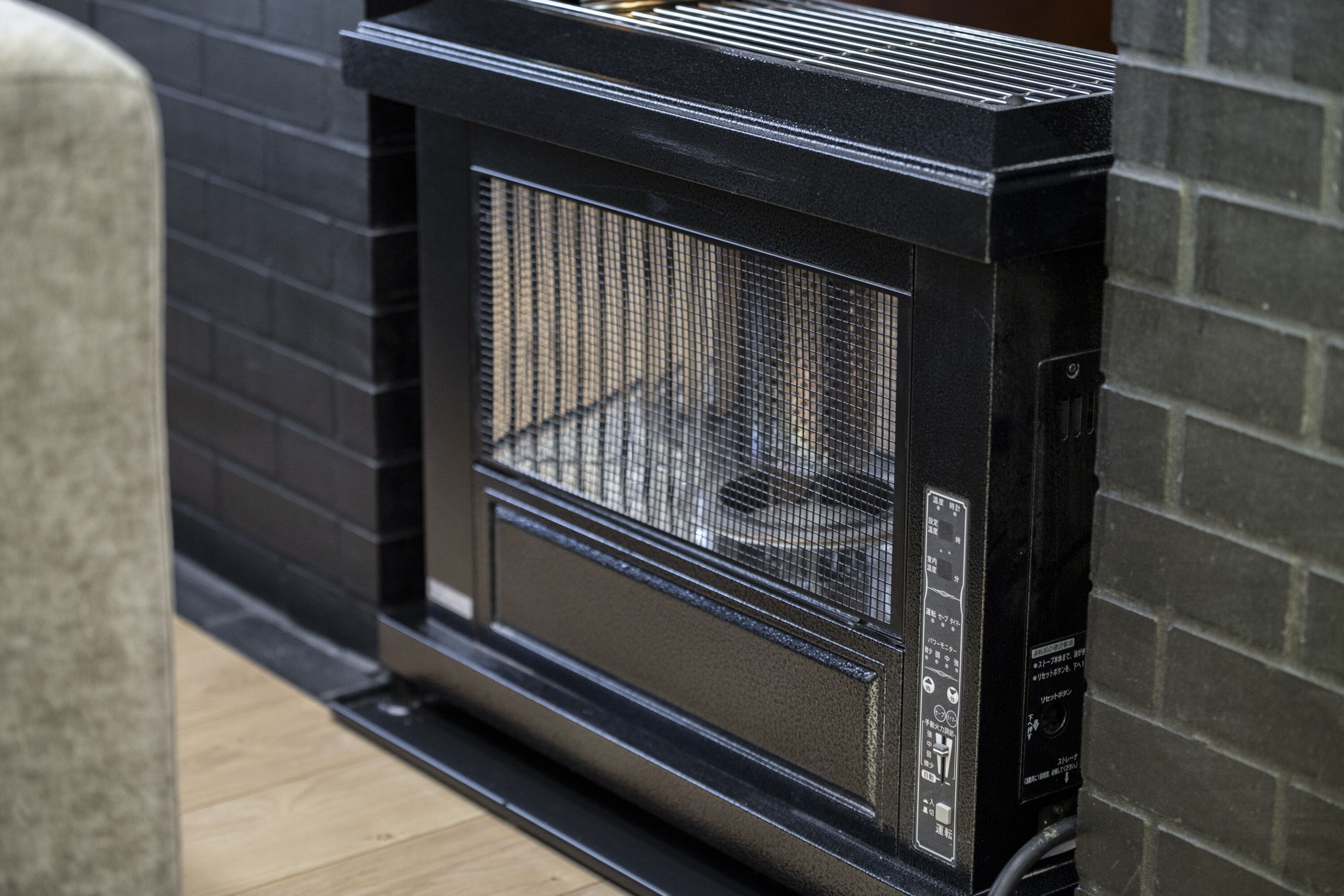 Un barbecue noir pour l’extérieur, doté d’un panneau de commande, placé contre un mur de briques.