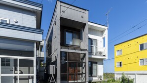 A modern multi-story residential building with a balcony, large windows, and a garage. - COSMIC HILL (Sapporo)