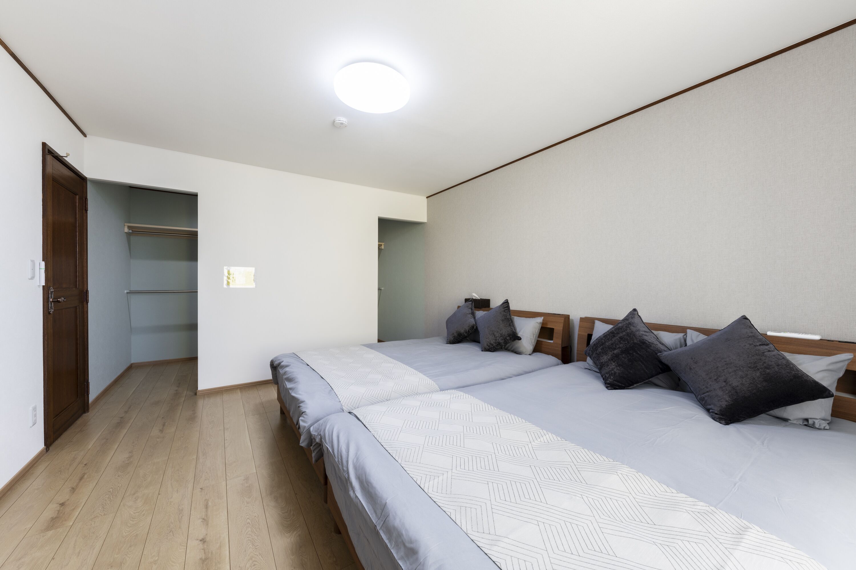 A bedroom with a bed, a wooden door, a closet, and a ceiling light.