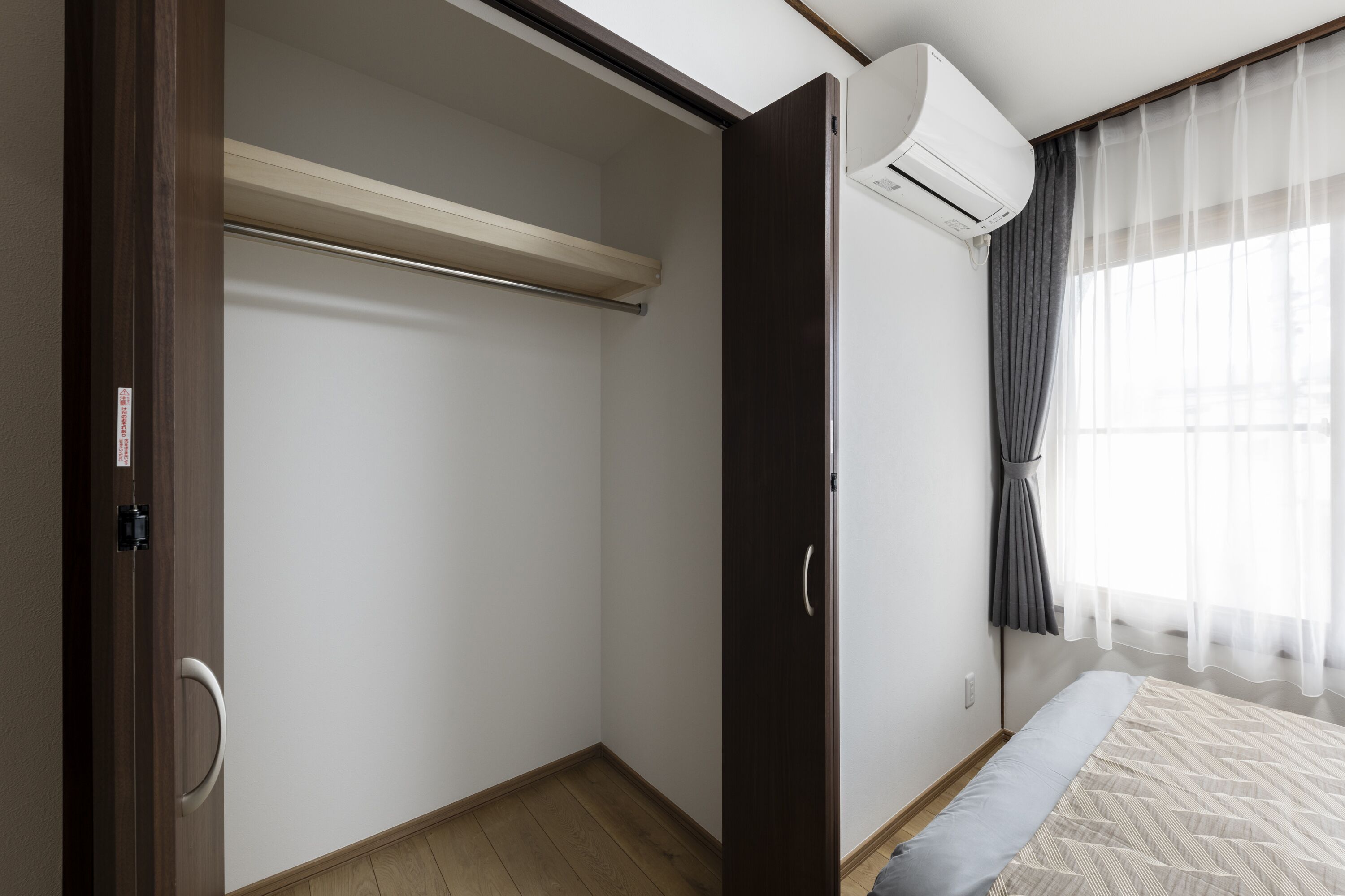 Un dormitorio con cama, armario, ventilador de techo y ventana con cortinas.