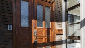 A wooden double door with glass panels, set in a building with a brick facade and a large window. - COSMIC HILL (Sapporo)
