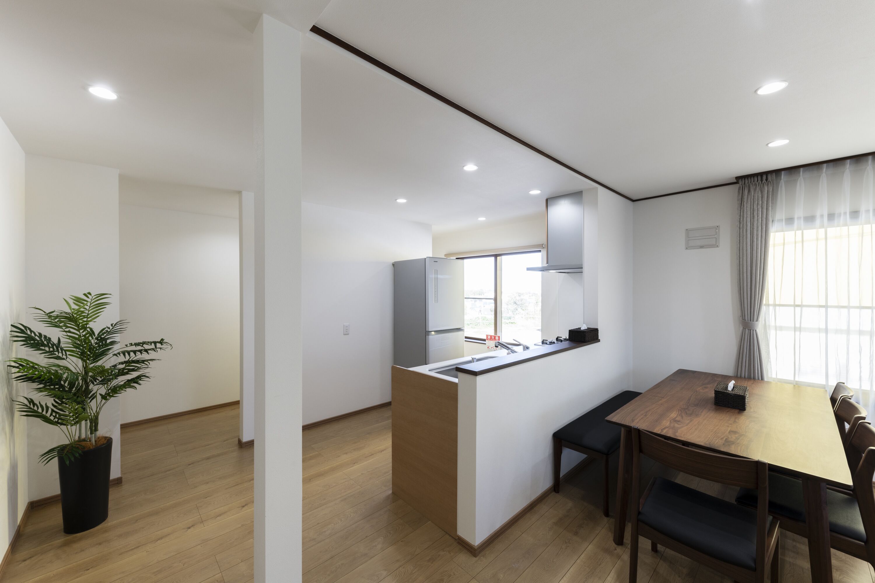 Una cocina moderna con una isla central, piso de madera y un comedor con mesa y sillas.