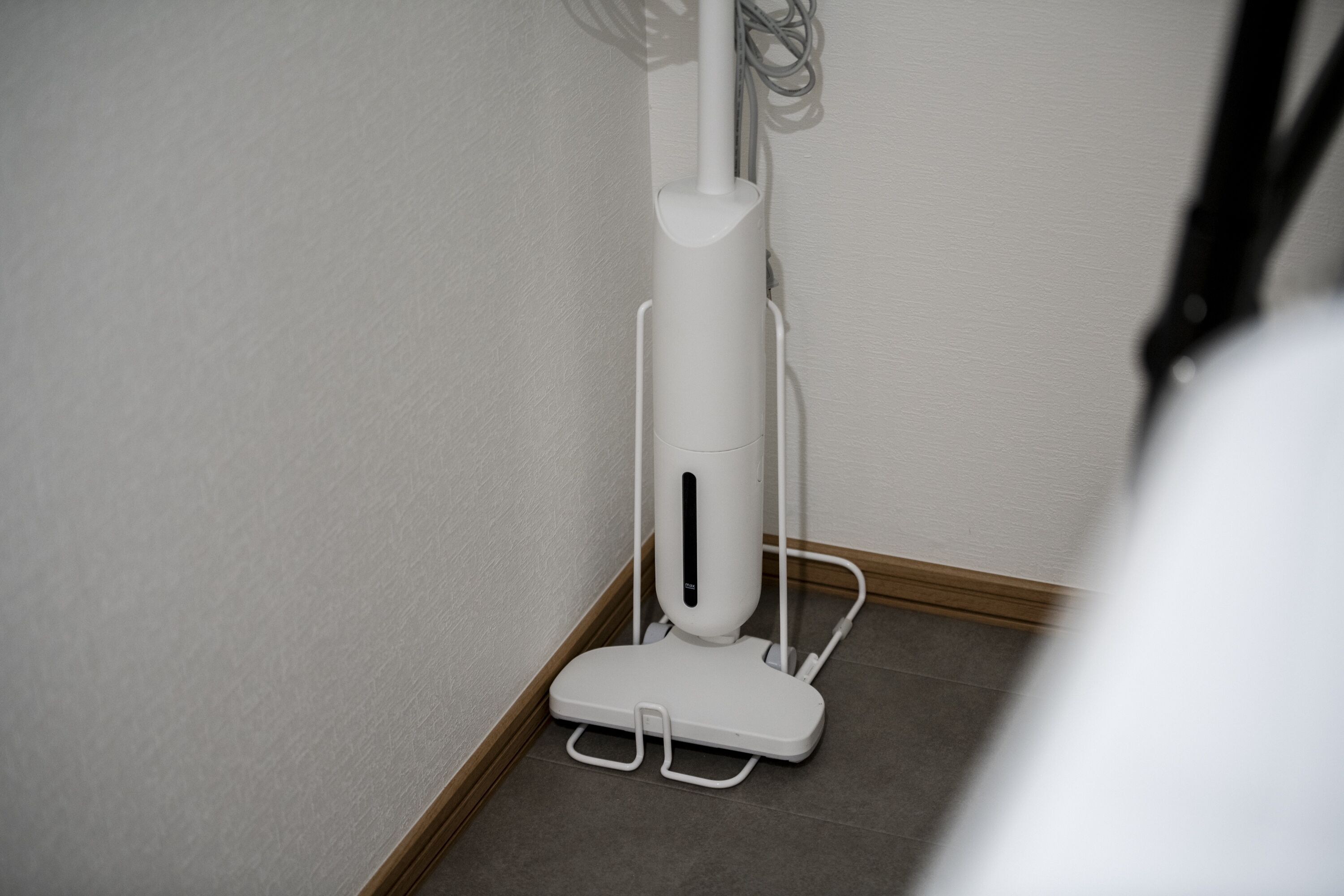 Un petit radiateur blanc, facile à déplacer, est placé dans un coin d’une pièce dont le sol est carrelé et qui est dotée d’une plinthe en bois.