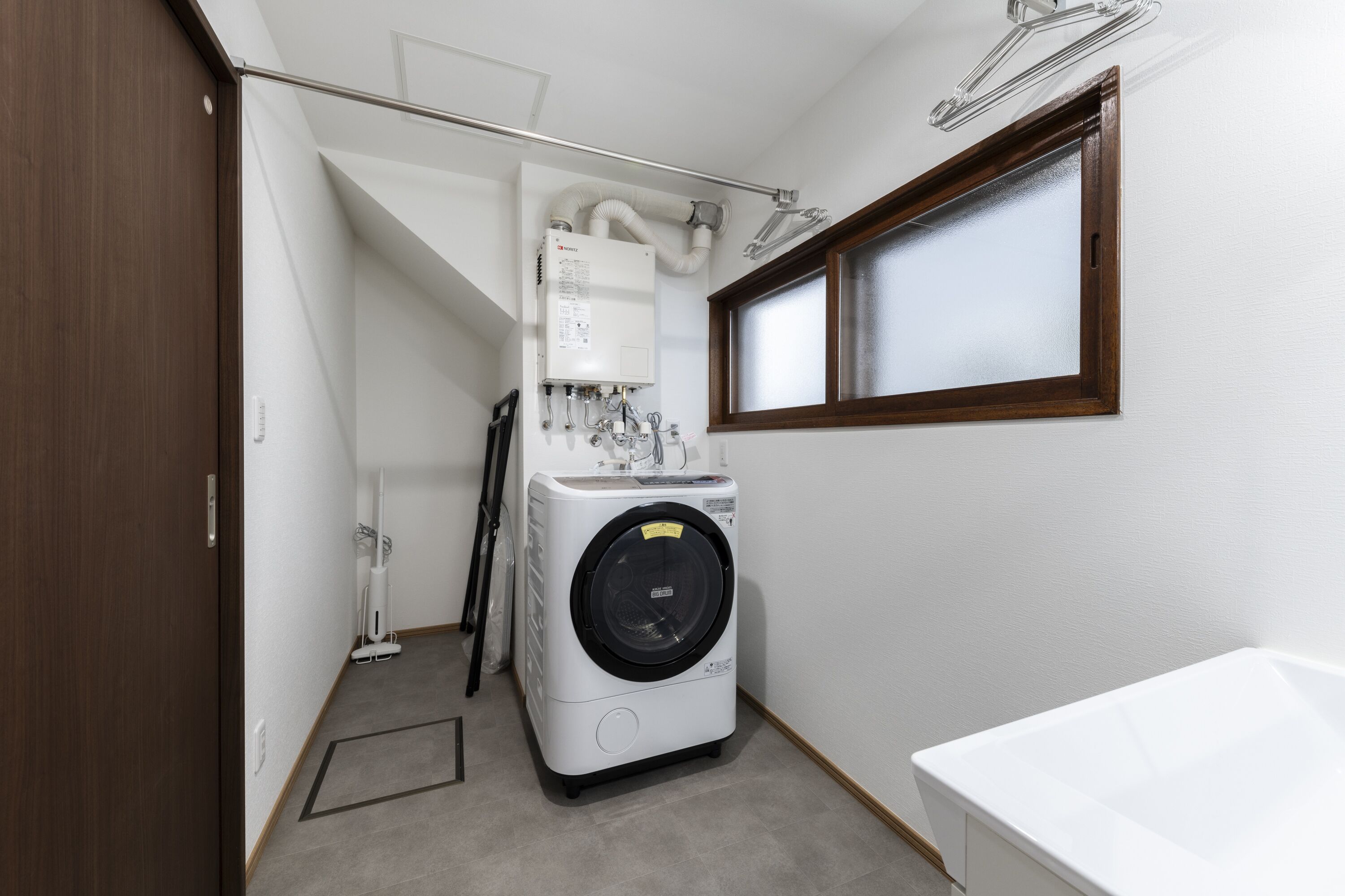 Une petite buanderie équipée d’un lave-linge, d’un sèche-linge et d’une fenêtre.